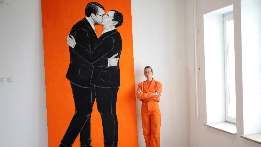 Ermira Murati posa ao lado de pintura que mostra o primeiro-ministro de Kosovo, Albin Kurti, e o presidente sérvio, Aleksandar Vucic, se beijando - REUTERS/Fatos Bytyci