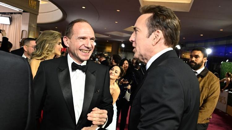 Ralph Fiennes, que concorreu com o filme "Conclave", e Nicolas Cage batem papo no tapete vermelho do Globo de Ouro