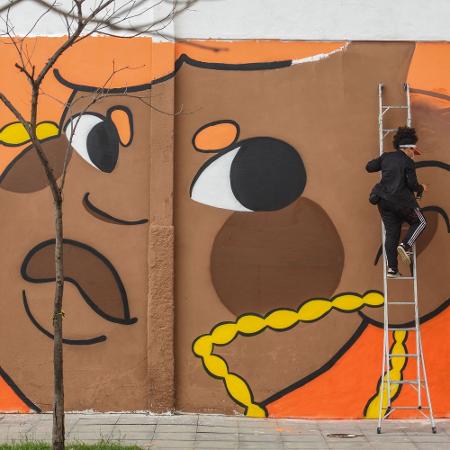 A artista Amora pintando um mural