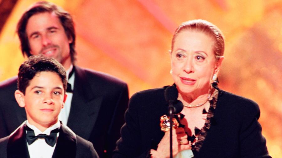 Fernanda Montenegro recebendo o Globo de Ouro de Melhor Filme em Língua Estrangeira junto ao diretor Walter Salles (ao fundo) e ao ator Vinícius de Oliveira (à esquerda) em 1999