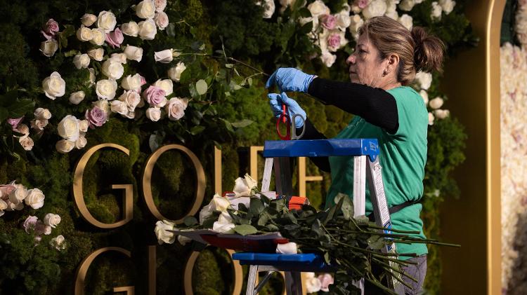 Florista coloca rosas no pano de fundo do tapete vermelho do Globo de Ouro