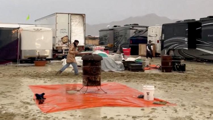 Uma pessoa caminha na lama após uma forte chuva, durante o evento Burning Man, no assentamento temporário no deserto de Black Rock City, Nevada, EUA, em 1º de setembro de 2023, nesta imagem estática de um vídeo de mídia social.