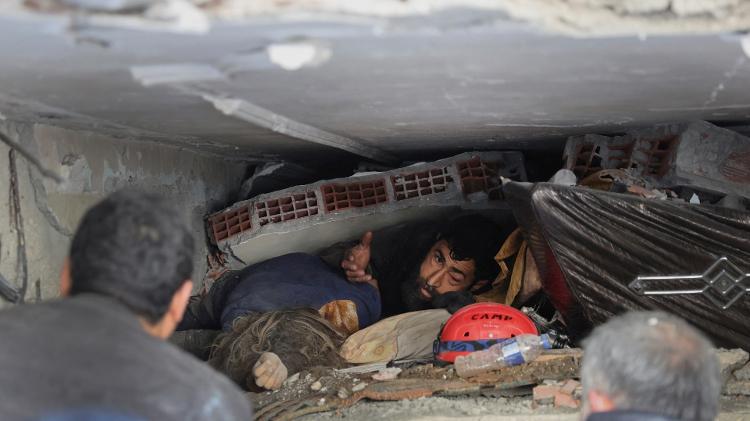 Abdulalim Muaini sob os escombros ao lado do corpo de sua esposa Esra, após um terremoto mortal em Hatay, Turquia, em 8 de fevereiro de 2023. 