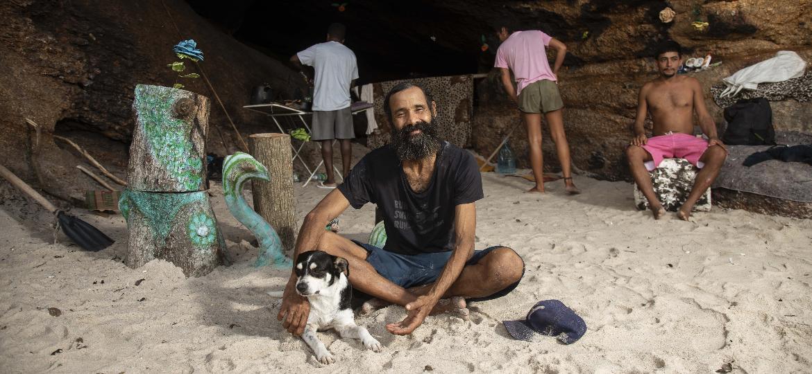 Cláudio Marsel (de camisa preta) com amigos, em frente à caverna em que mora há mais de oito anos, embaixo do MAC-Niterói - Ricardo Borges/UOL