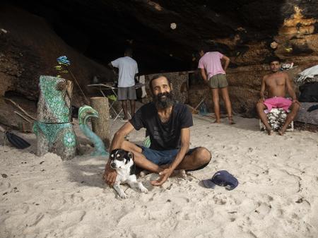 Cláudio Marsel (de camisa preta) com amigos, em frente à caverna em que mora há mais de oito anos, embaixo do MAC-Niterói - Ricardo Borges/UOL