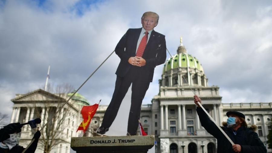Donald Trump de papelão é retirado por manifestantes do lado de fora da sede do governo da Pensilvânia, nos EUA - Mark Makela/Getty Images
