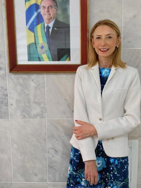 Angela Gandra posa ao lado de foto oficial do ex-presidente Jair Bolsonaro, em Brasília