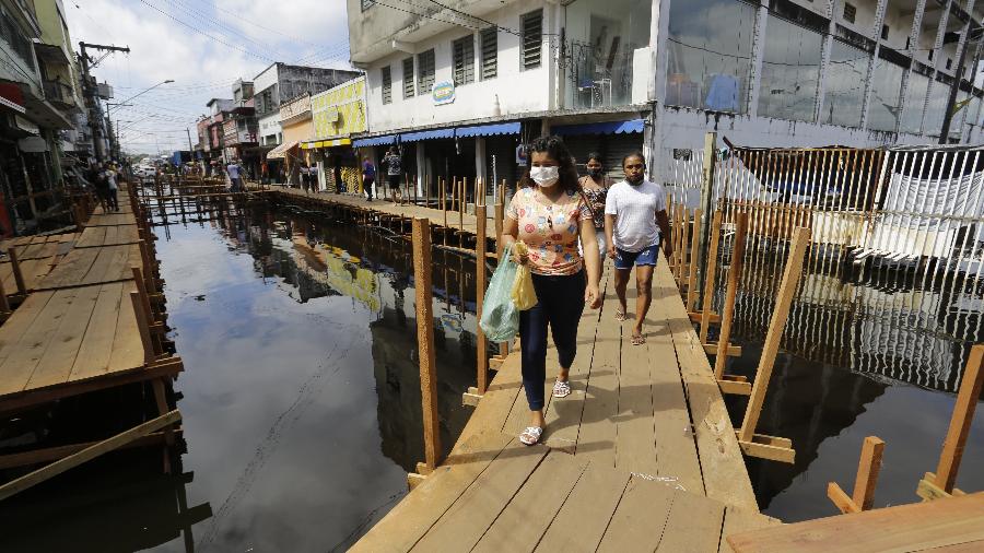 Pessoas caminham sobre pontes de madeira improvisadas em área comercial, no centro de Manaus, devido à cheia do Rio Negro - Nelson Antoine/Folhapress