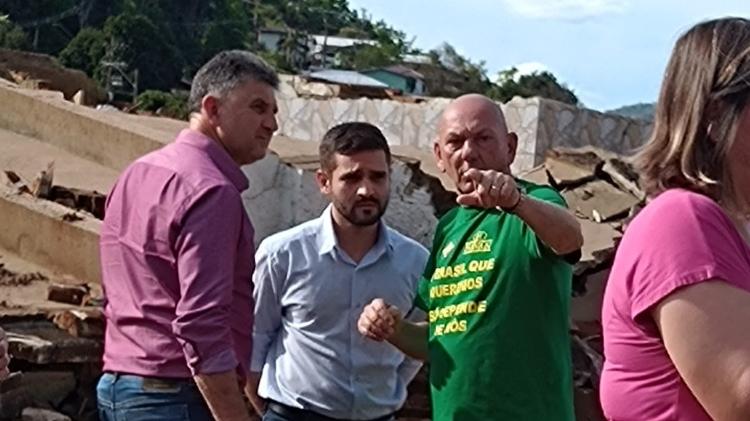 Foto "roubada" por Claudiana mostra Luciano Hang com o prefeito (no meio) na entrada do cemitério de Muçum