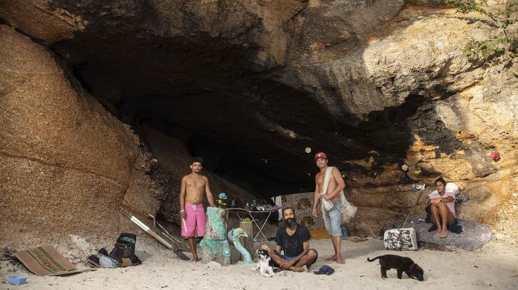 Cláudio Marsel (de camisa preta) com amigos, em frente à caverna em que mora há mais de oito anos, embaixo do MAC-Niterói - Ricardo Borges/UOL - Ricardo Borges/UOL