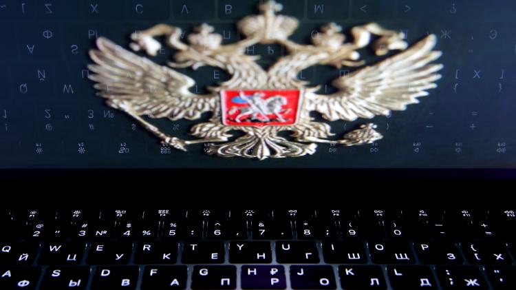 O escudo de armas da Rússia reflete no teclado de laptop, mostrando a influência estatal sobre a internet local - Maxim Shemetov/Reuters