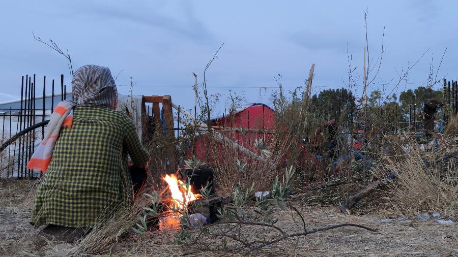 Refugiada se esquenta em uma fogueira improvisada nas ruas de Lesbos, na Grécia - André Naddeo/UOL