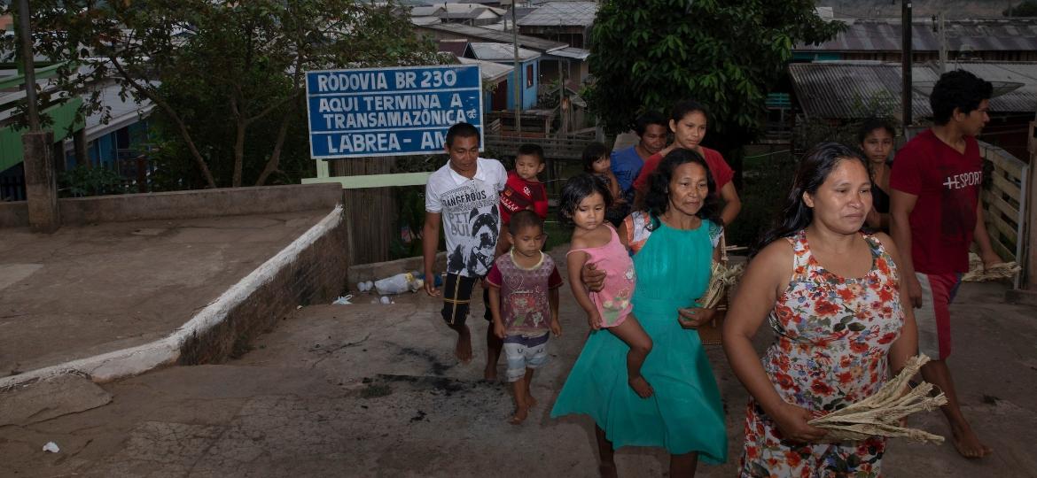 Índígenas da etnia apurinã passam pela placa que indica o término da rodovia Transamazônica, no município de Lábrea (AM) - Caio Guatelli/UOL