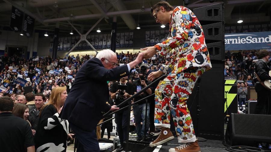 Julian Casablancas, vocalista da banda Strokes, ajuda o pré-candidato democrata Bernie Sanders a subir no palco de comício - Joe Raedle/AFP