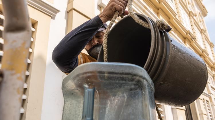 Juan Romero, 57, tira água de um poço no centro da cidade de Macaraibo.Ele enche tambores para levar a bairros onde o serviço é intermitente