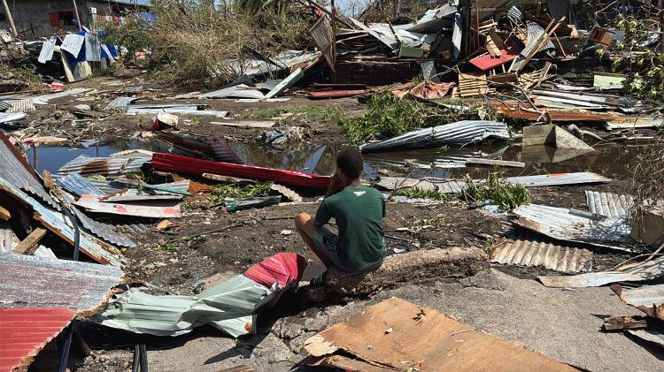 Menino observa as ruínas de casas, após o ciclone Chido, em Mayotte