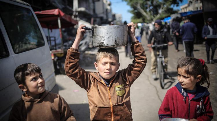 Crianças se reúnem em ponto de distribuição de alimentos em Khan Yunis, no sul da Faixa de Gaza