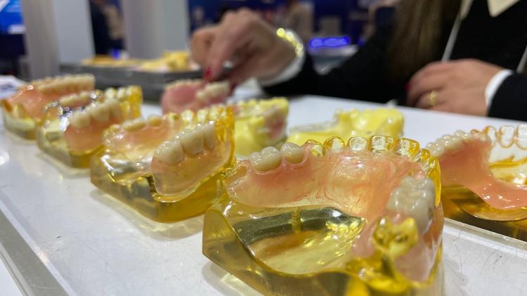Vendedora mostra modelos de dentaduras feitas com resinas e silicones em estante de fabricante - Rodrigo Bertolotto/UOL - Rodrigo Bertolotto/UOL