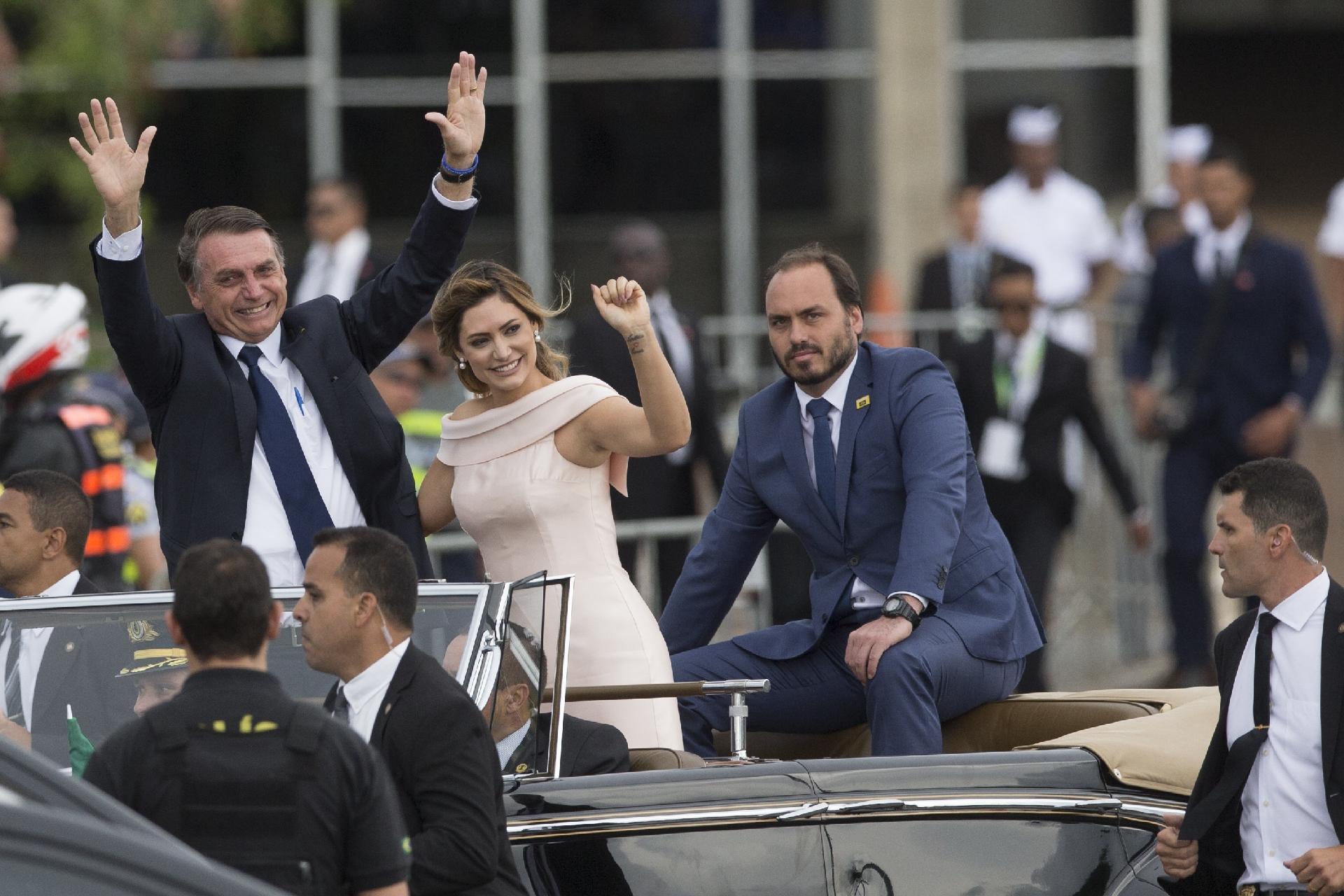 Jair Bolsonaro acena para o público ao lado de Michelle e do filho Carlos em desfile no Rolls-Royce da Presidência, em 2019  - undefined