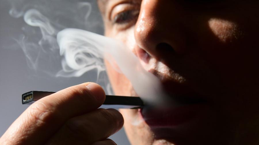 Rapaz fuma o cigarro eletrônico da Juul, que mais parece um pen-drive - AFP