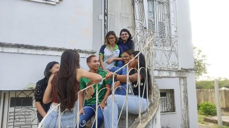 Grupo de estudantes conversando na escada do casarão