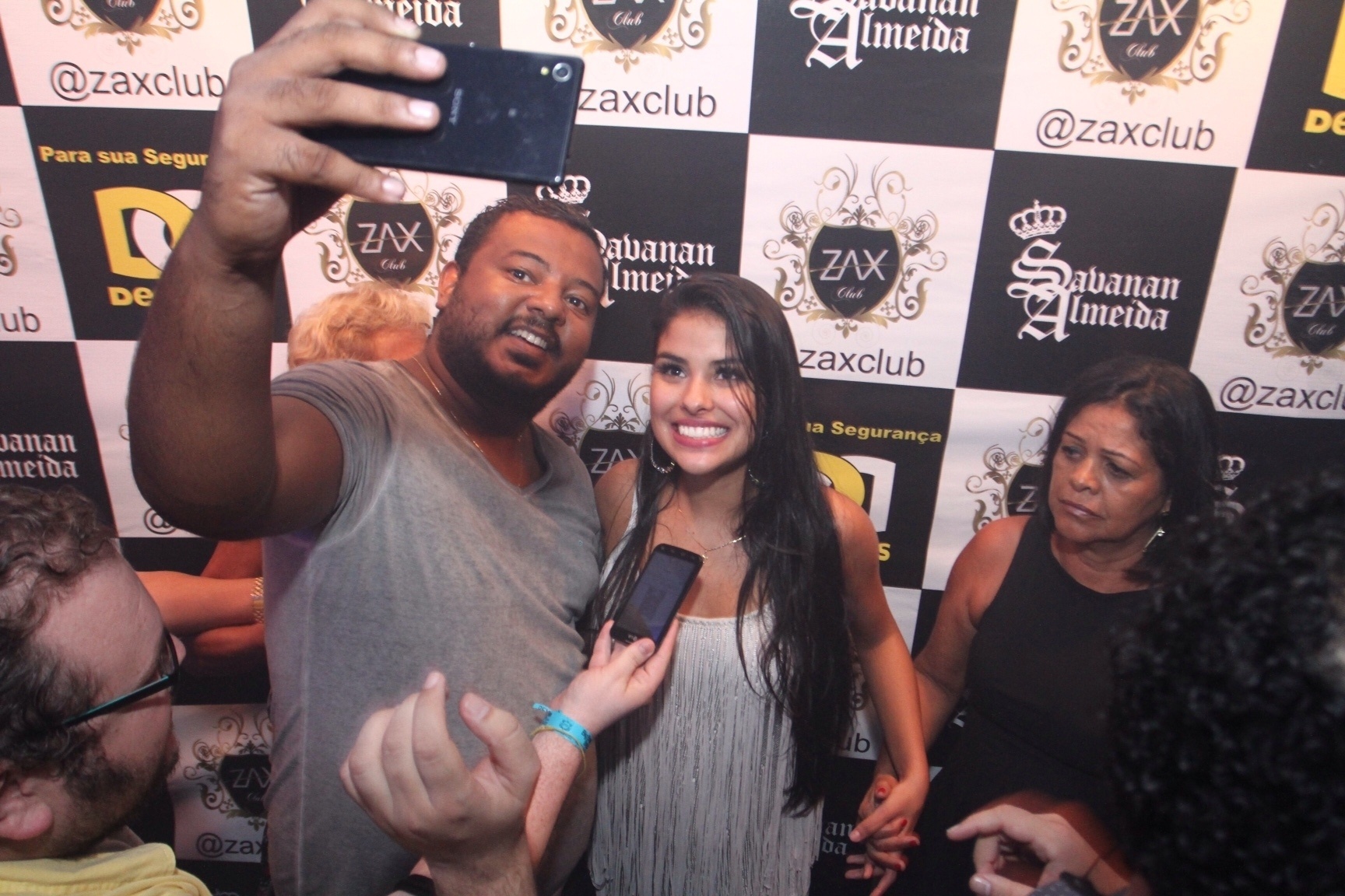 6.abr.2016 - Sem largar a mão da mãe, Munik posa para fotos com fãs - AgNews