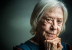 Fernanda Montenegro séria, olhando para a câmera com mãos próximas ao queixo, em close, no canto direito de foto