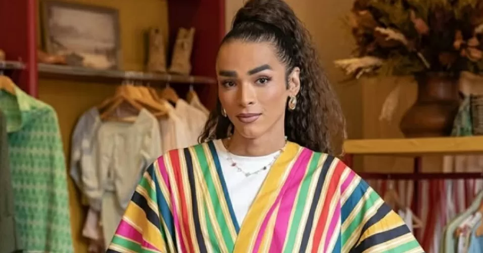 Isis Broken de roupa colorida com várias roupas ao fundo