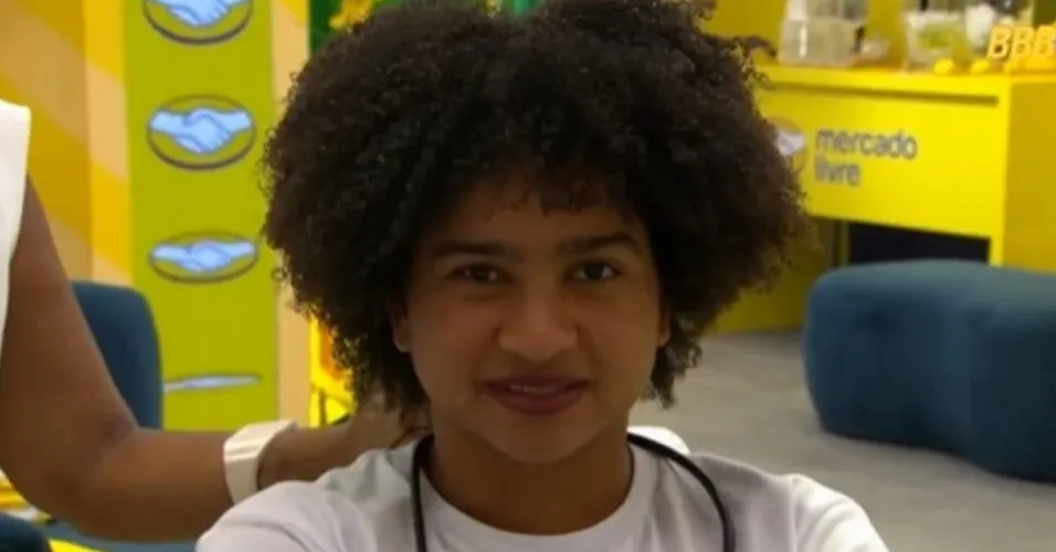 Milena de camiseta branca, falando, sentada