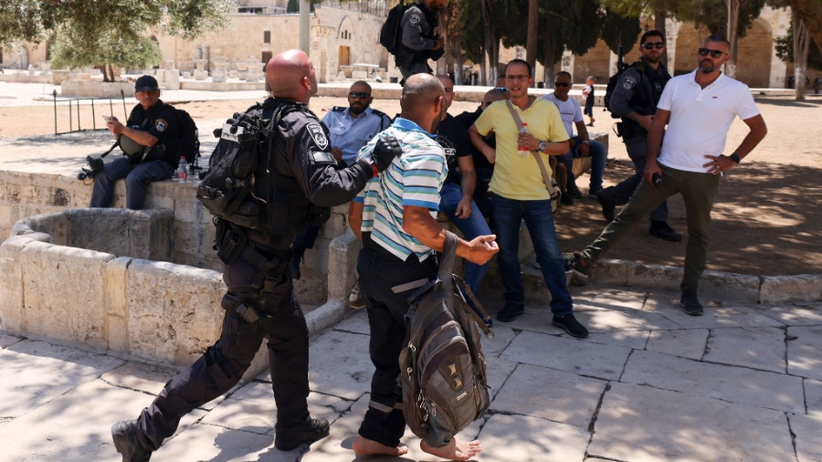 Membros das forças de segurança israelenses prendem um palestino, enquanto um grupo de judeus ortodoxos entra no complexo da mesquita de al-Aqsa em Jerusalém - Ahmad Gharabli / AFP