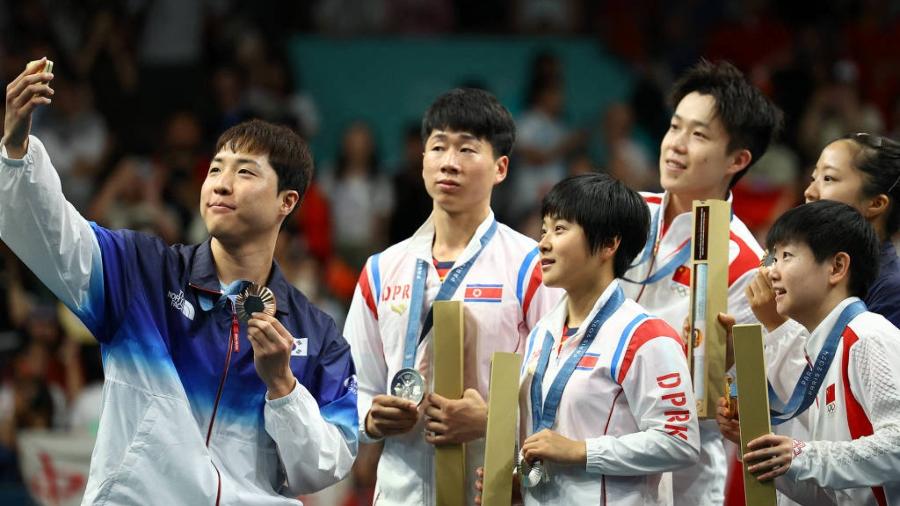 Duplas mistas de Coreia do Norte, Coreia do Sul e China fazem selfie após pódio no tênis de mesa