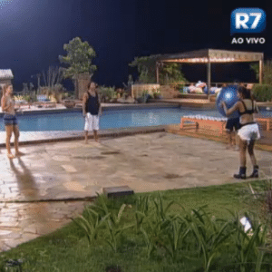 Peões brincam com bola próximos à piscina